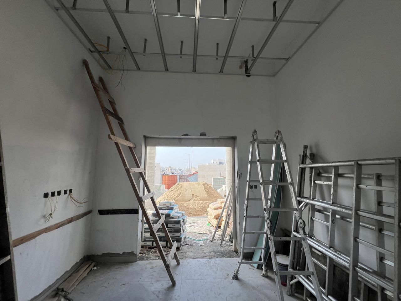 Interior room during construction with plastered walls, ladders and unfinished openings