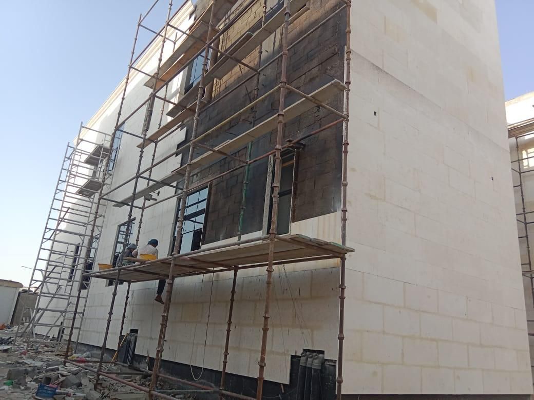 Scaffolding against the façade of a villa under construction during stone cladding works